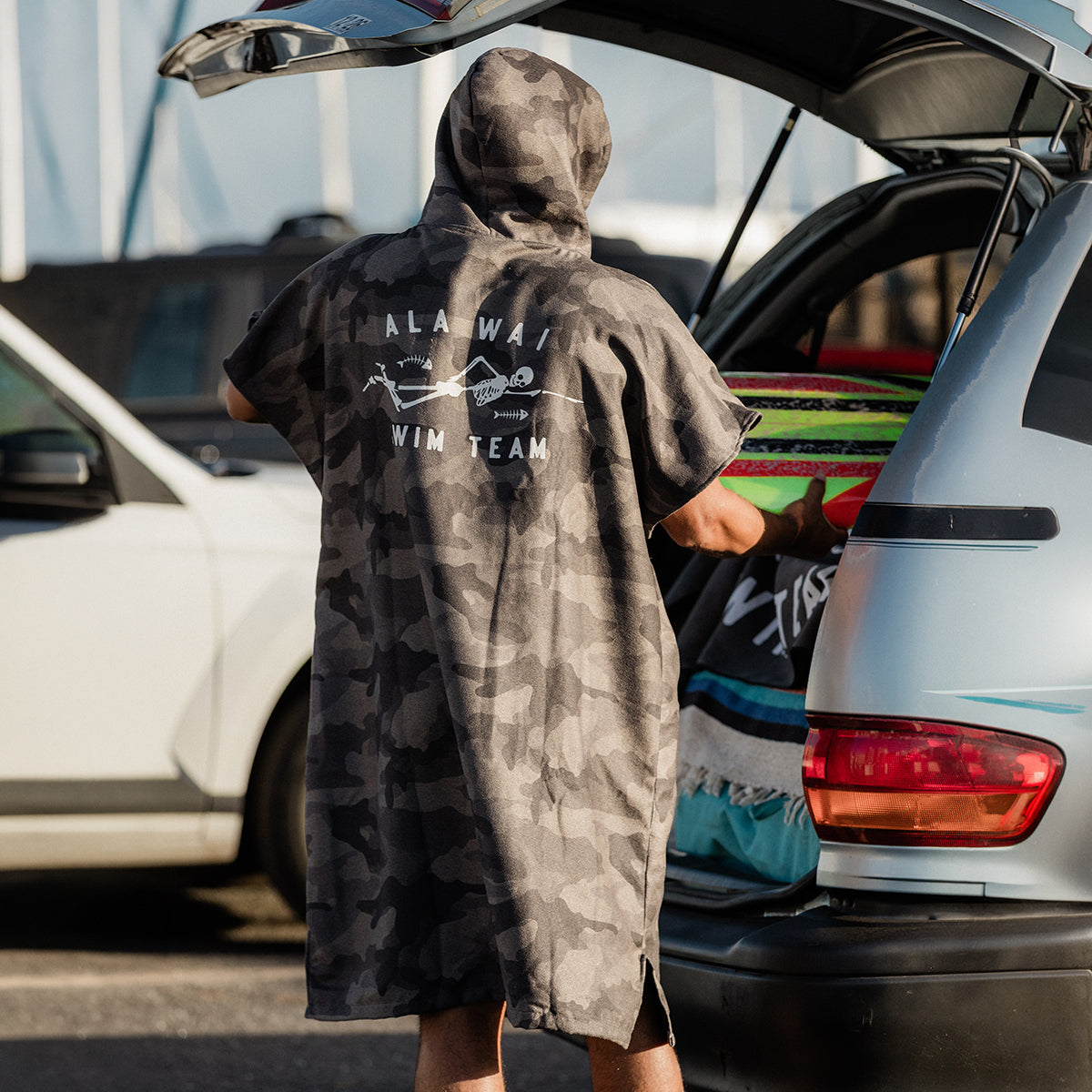 High absorbency changing poncho with surfboards near a car trunk.