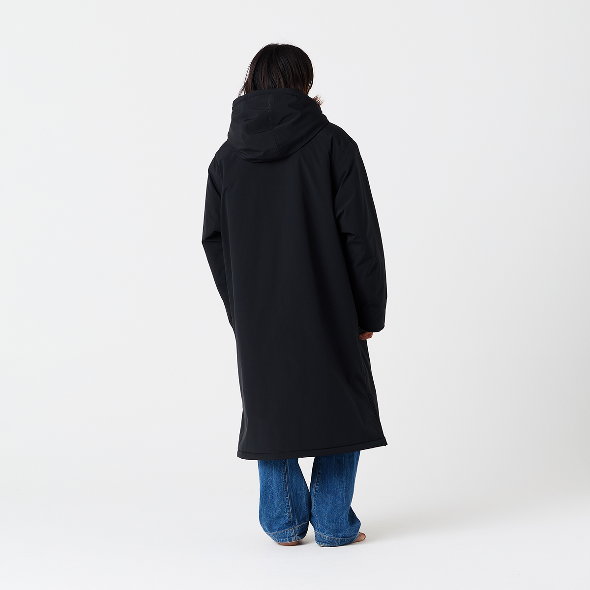 Black all-weather parka with blue jeans, back view.