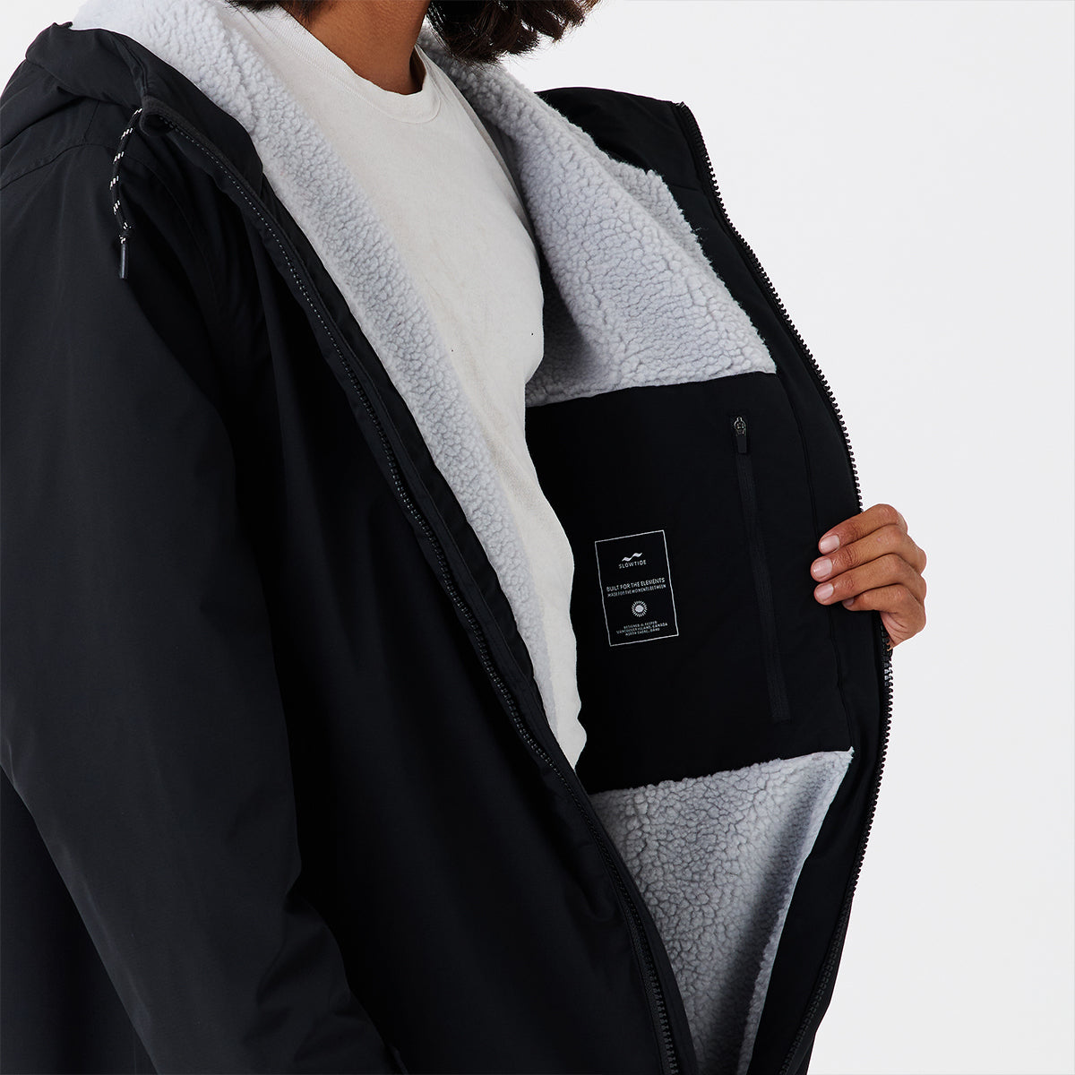 Black jacket with light gray sherpa lining and waterproof shell, opened to show interior.