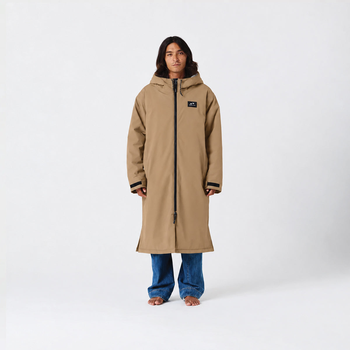 Tan waterproof parka, hip-length, with jeans displayed on plain white background.