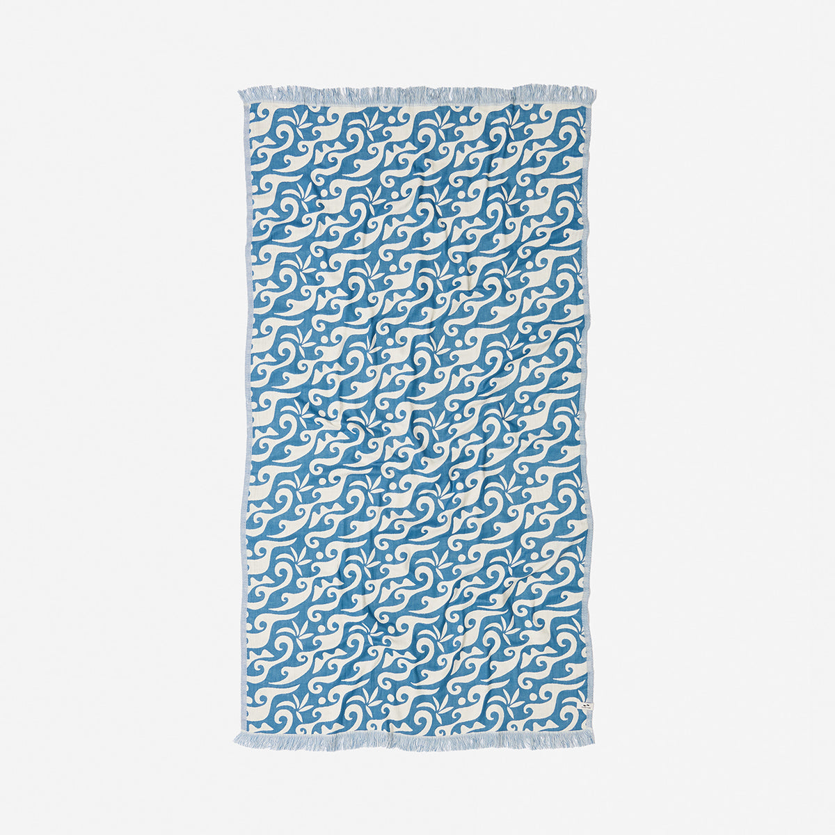 Beach towel with ocean blue swirling wave pattern and fringed edges for beach use.