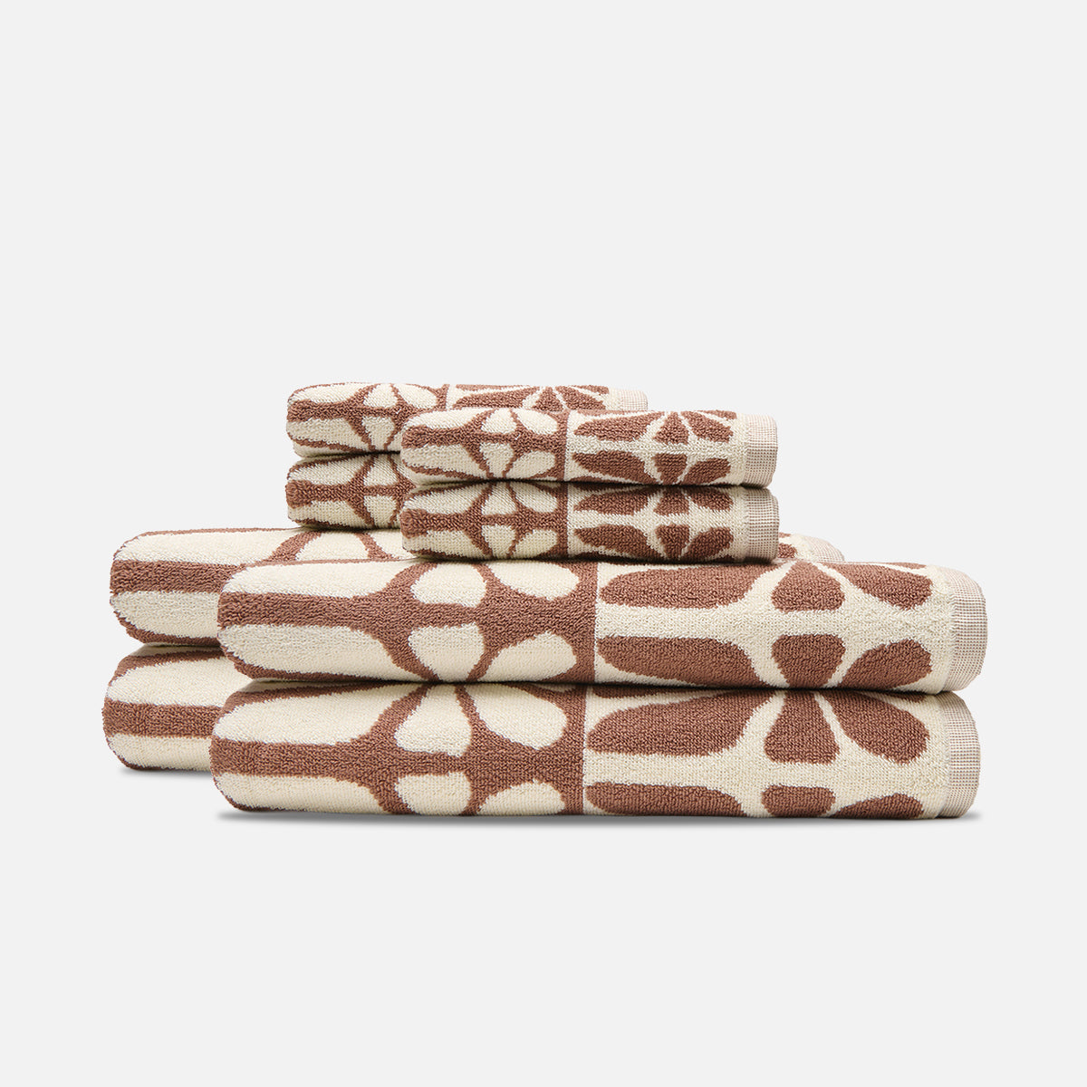 Absorbent towels, beige and brown, floral and geometric pattern, stacked.