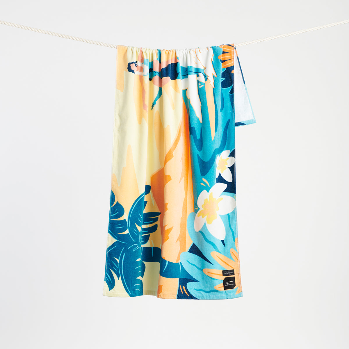 Floral cotton beach towel with colorful design hanging on a clothesline.