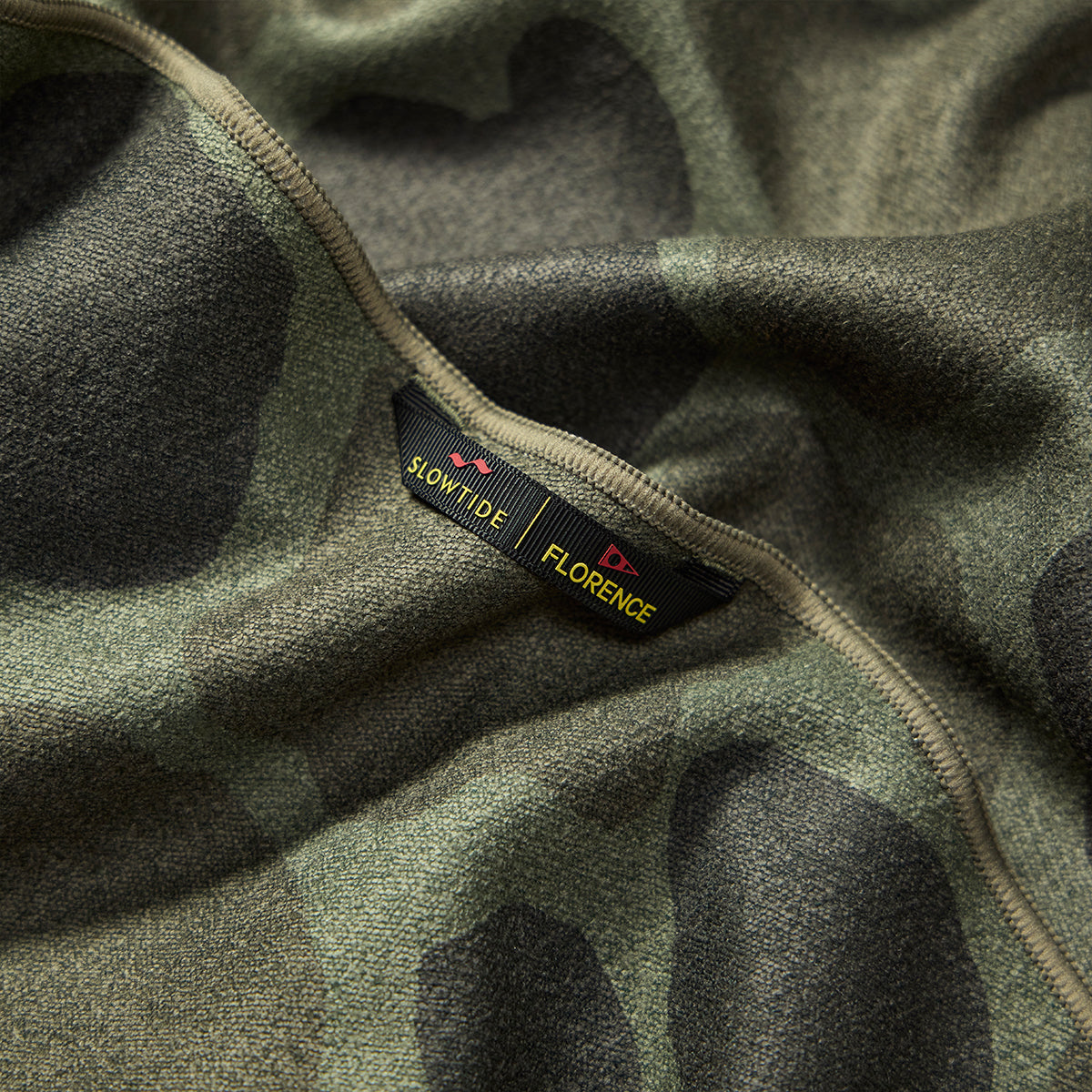 Towel with camo print and sewn label, close-up view.