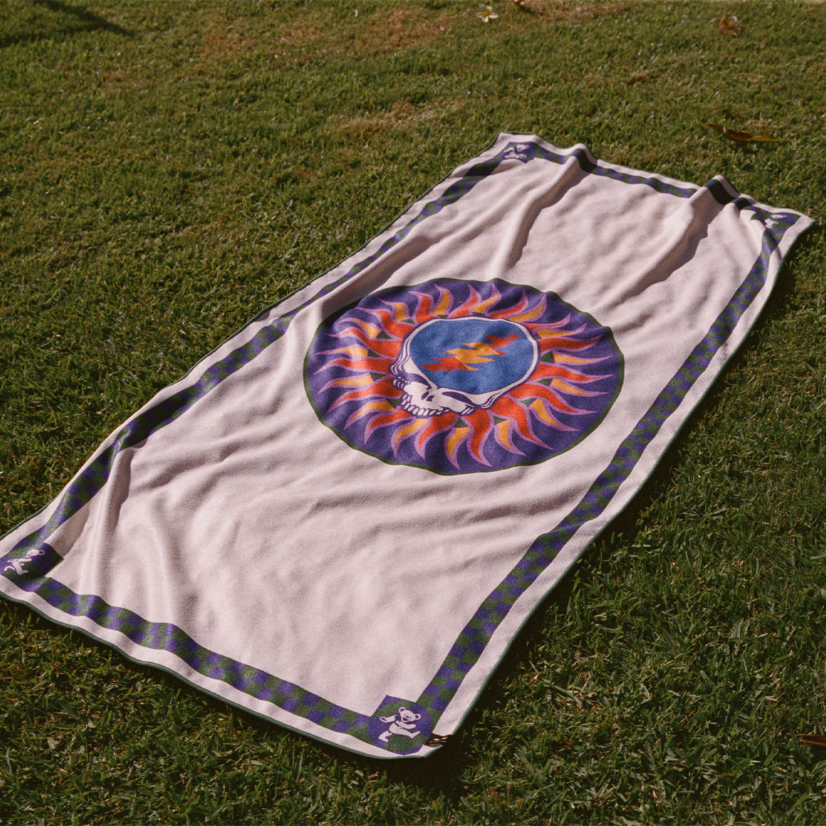 Quick-drying towel with fiery skull pattern on grass.