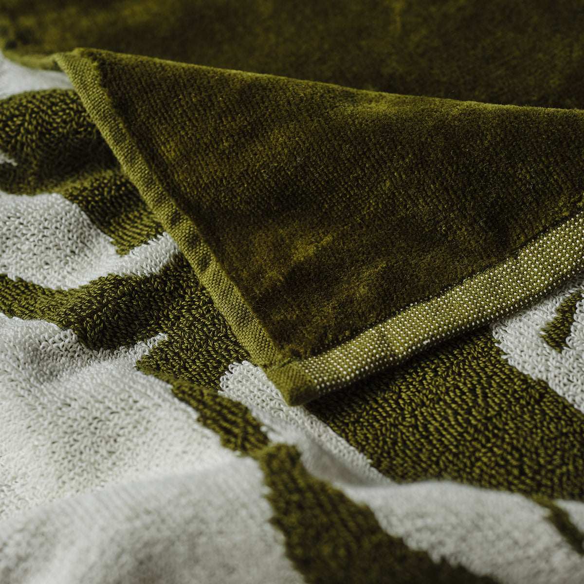 Woven cotton towel in green and white with folded corner.