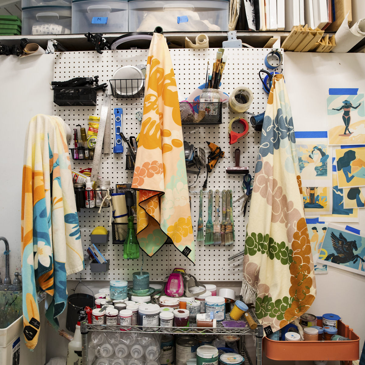 Sustainable cotton towels displayed on art studio pegboard with paint supplies.