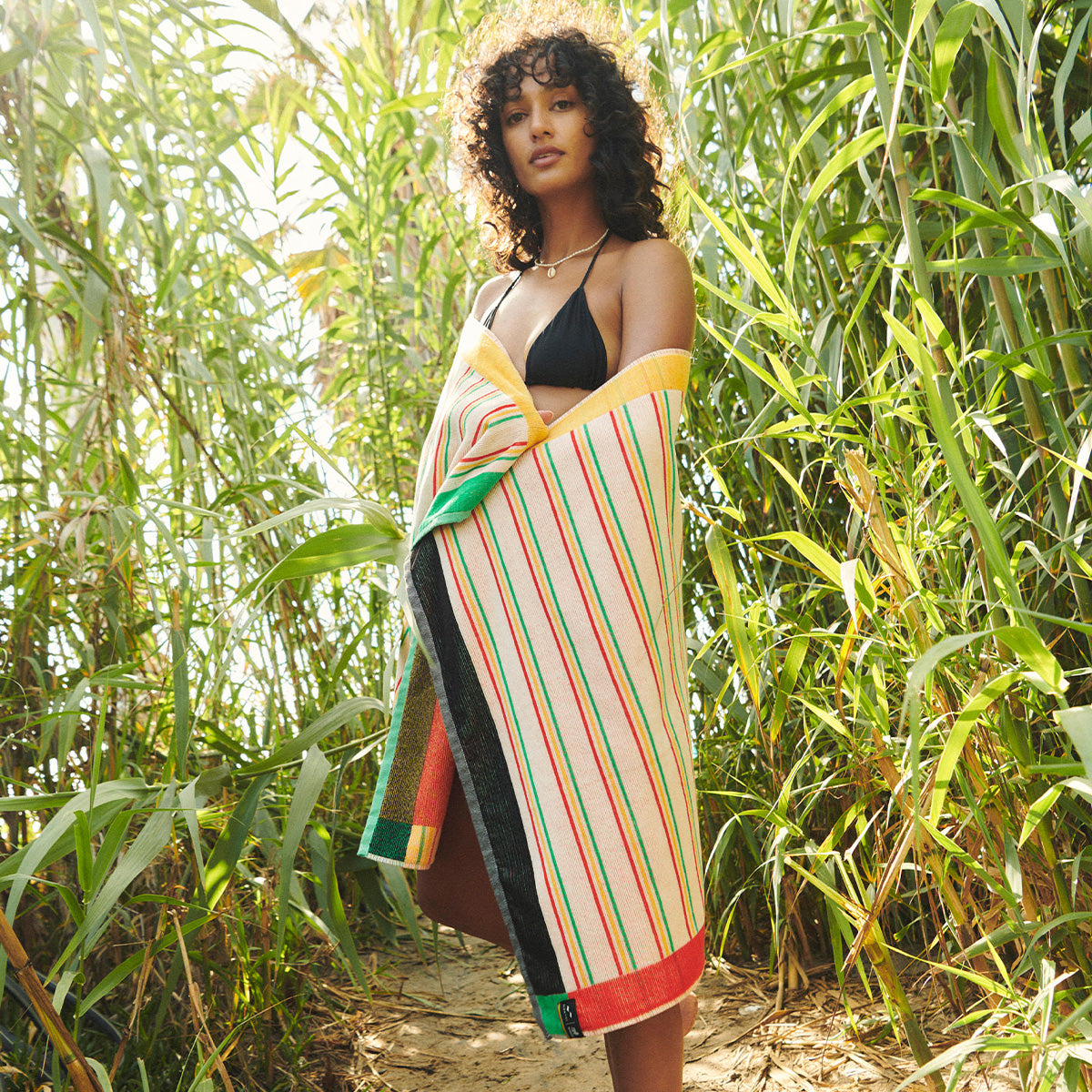 Cotton towel with colorful pattern and bikini in grass.