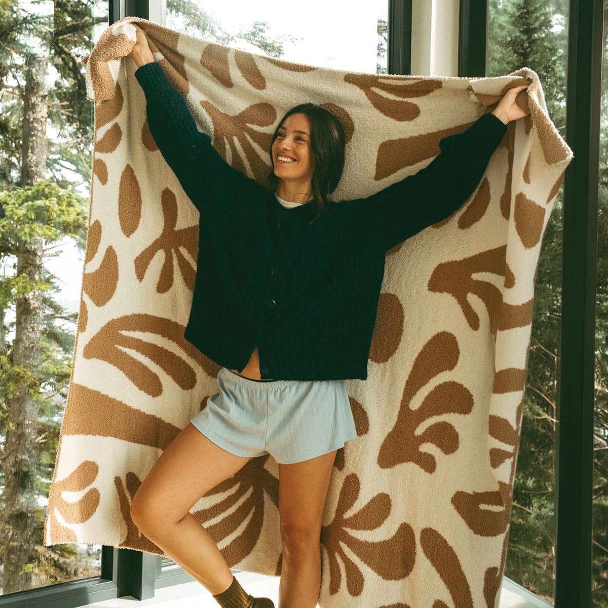 Plush knit throw in a brown and cream abstract tropical leaf pattern.