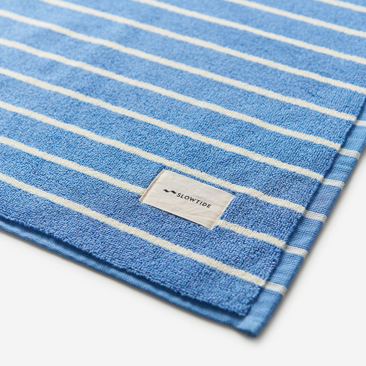 Cotton towel with white stripes, absorbent and soft, suitable for use as a bath mat.