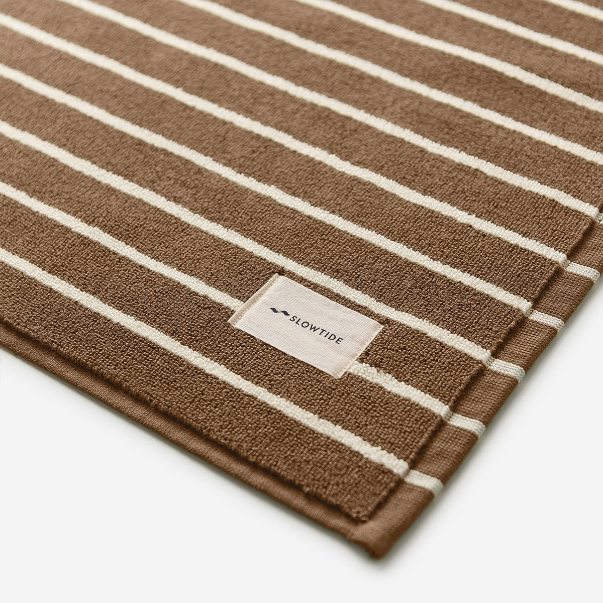 Brown cotton towel with white stripes, sustainable material, absorbent fabric.