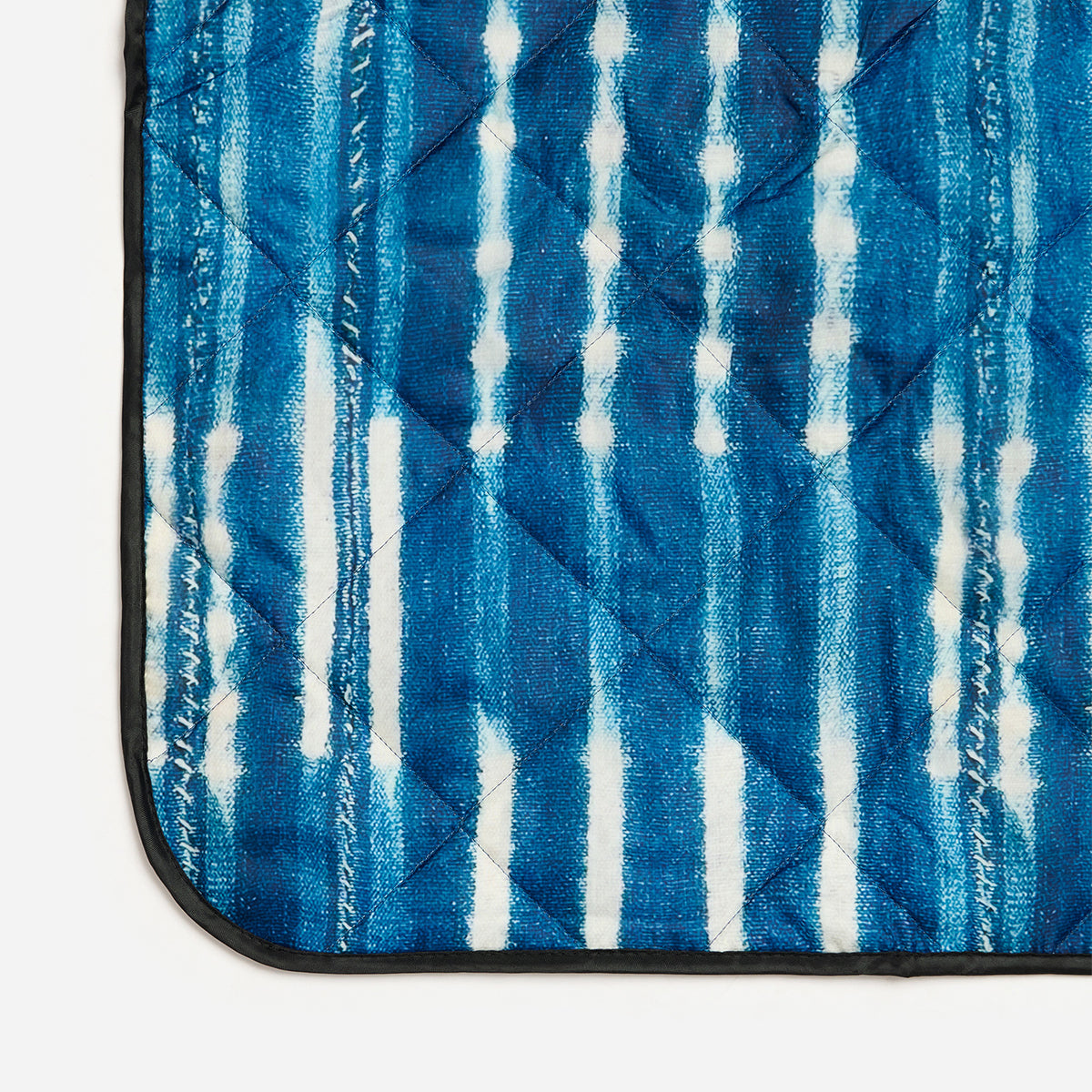 Quilted water-resistant mat featuring blue and white vertical tie-dye stripes.