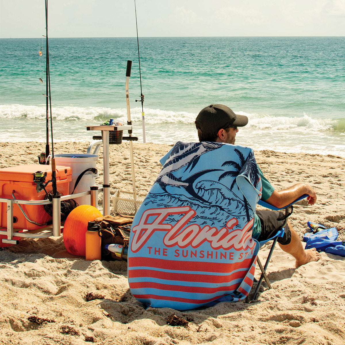Beach chair with quick-drying towel and fishing gear on sand.