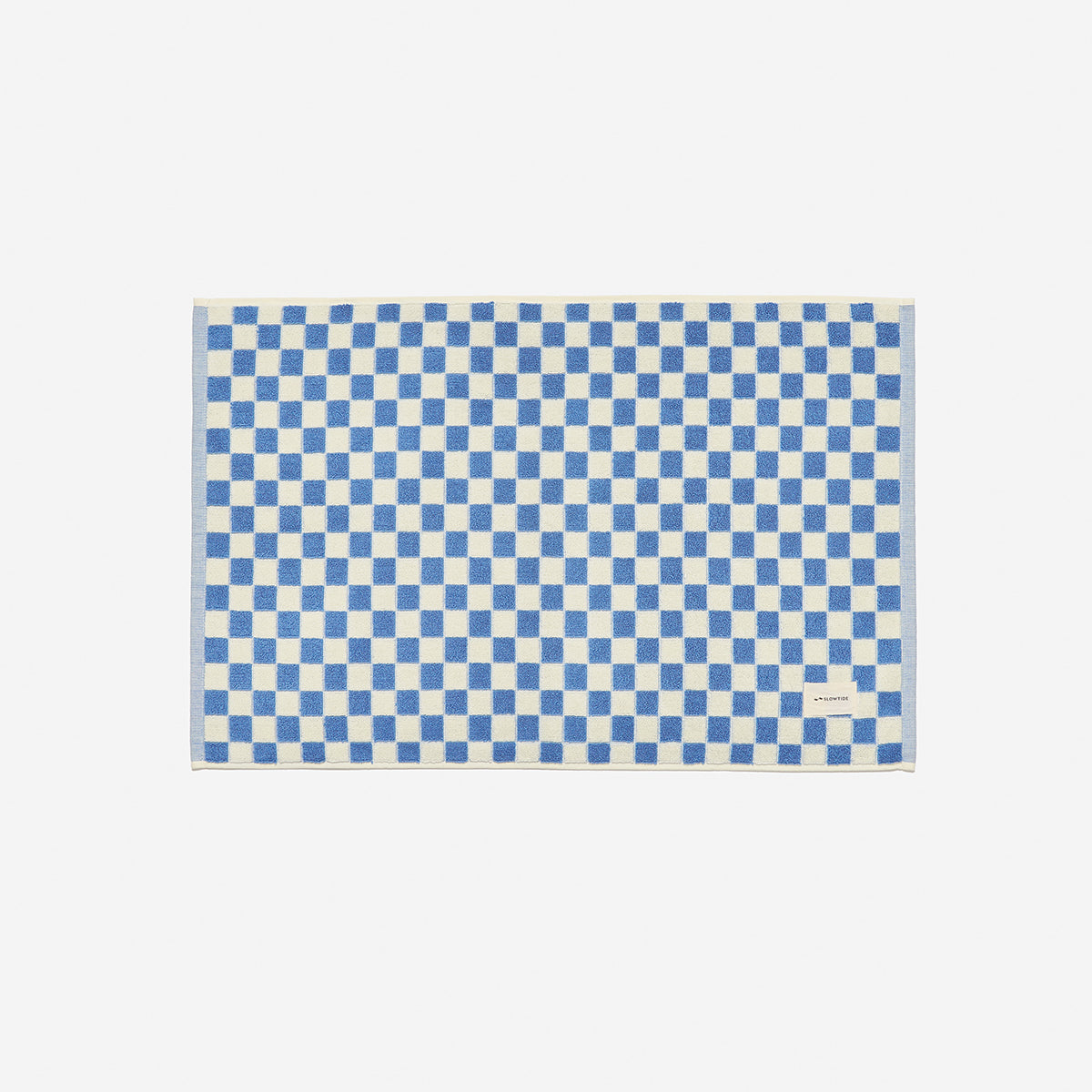 Cotton bath mat with blue and white checkerboard pattern, small label at bottom right.