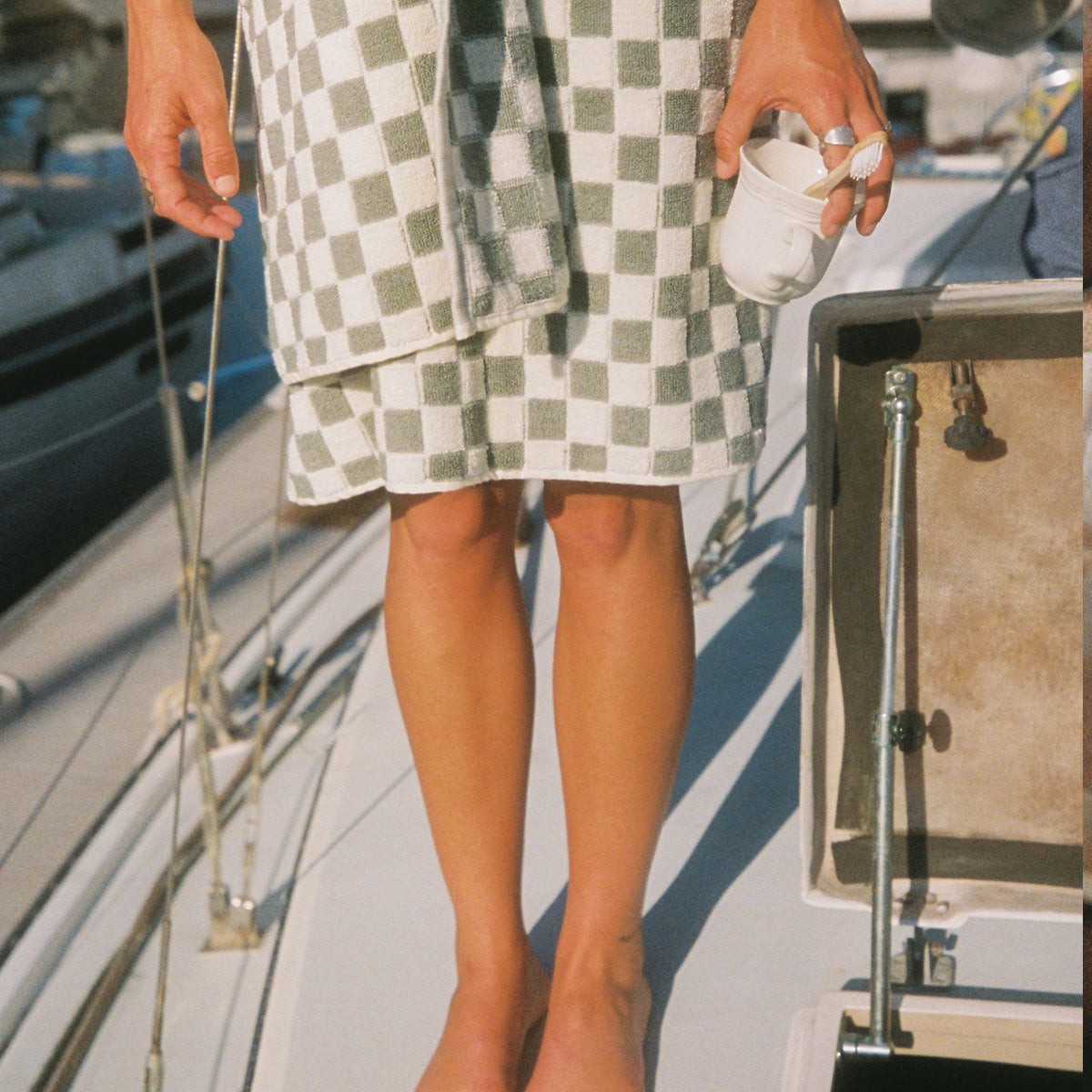 Checkerboard pattern bath towel with white cup, shown on boat deck.