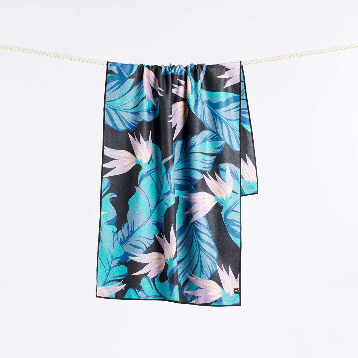 Quick-drying towel with blue tropical leaf and pink flower pattern on display.
