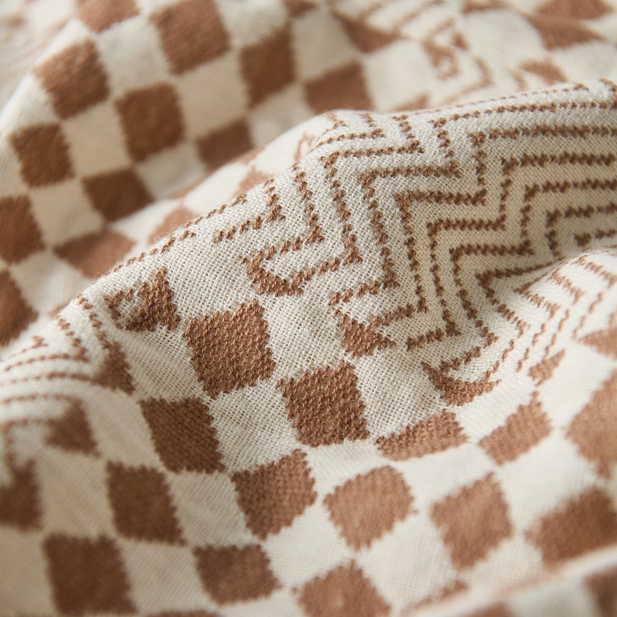 Beach towel, brown and cream fabric with checkered and zigzag patterns, sand resistant.
