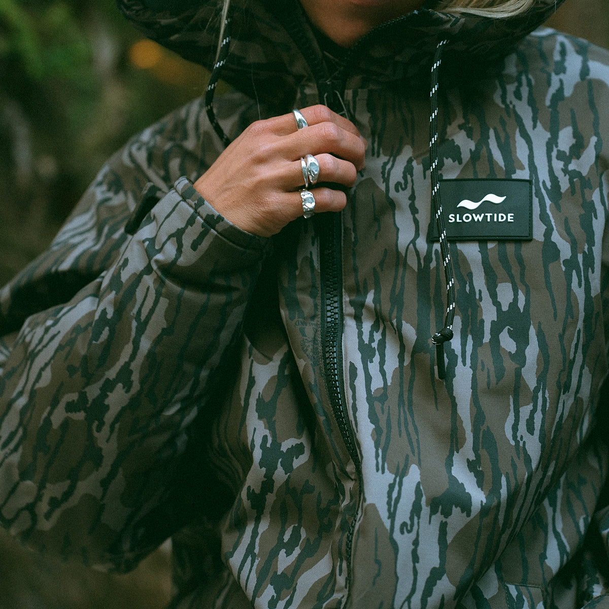 Camo insulated jacket with silver zipper rings and logo patch.