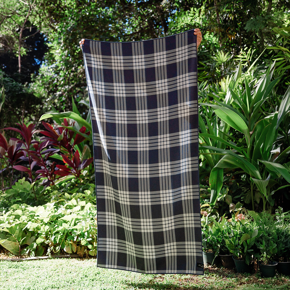Sustainable towel with large size, shown outdoors among lush green plants.