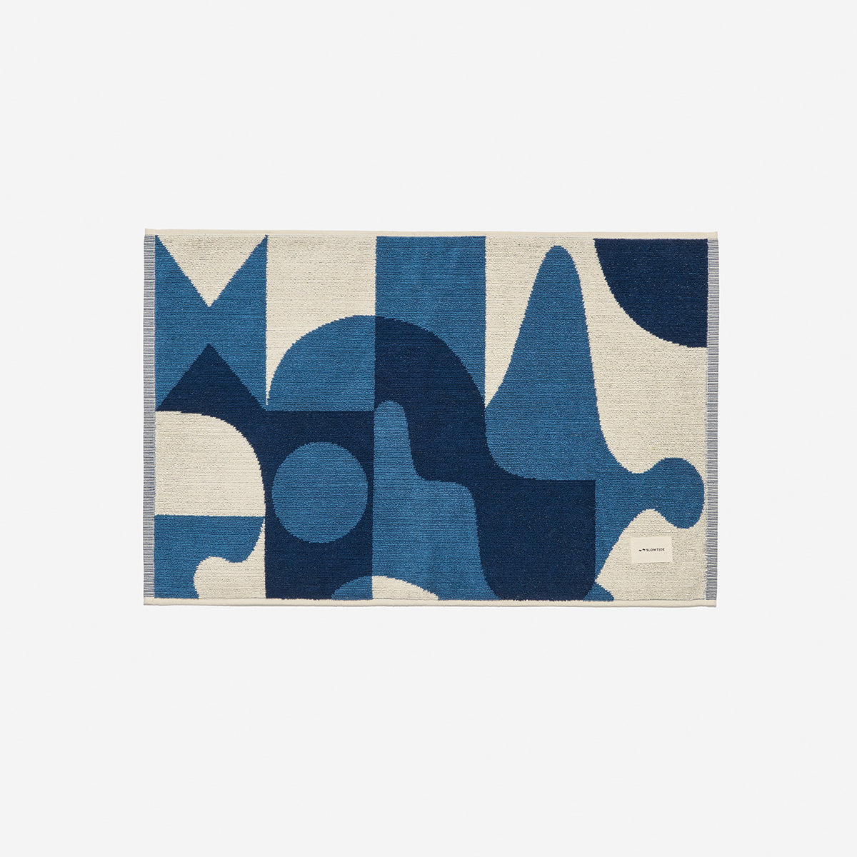 Cotton bath mat with blue and white geometric pattern.