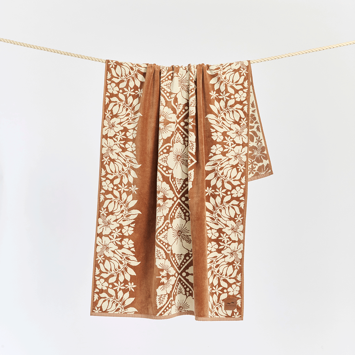 Jacquard beach towel in brown and beige with geometric pattern displayed hanging.