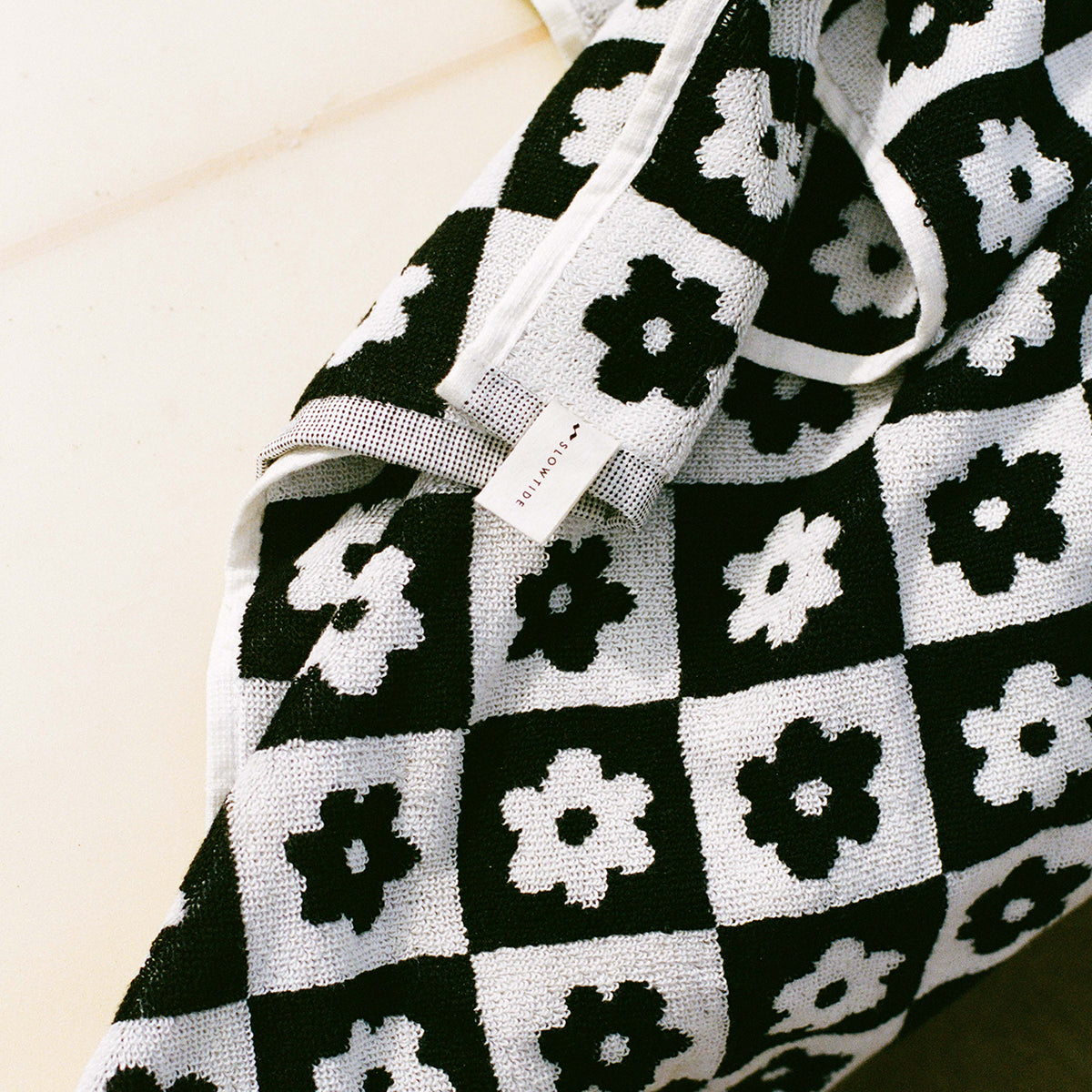 Bath towel, cotton, black and white checkered with flower pattern and small tag attached.