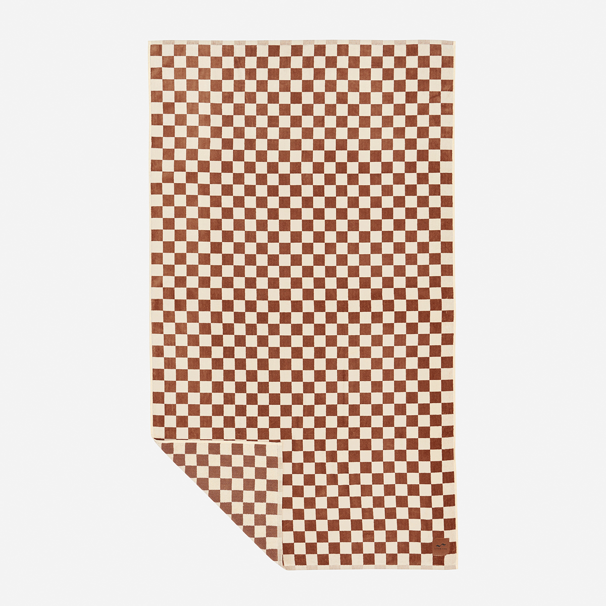 Beach towel in brown and cream checkered jacquard with a folded corner.