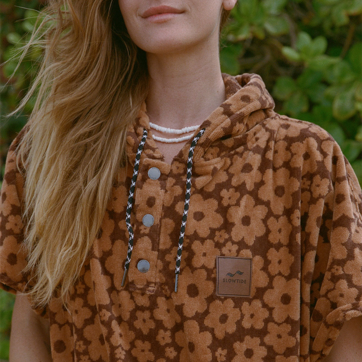 Brown absorbent poncho with floral pattern shown outside.