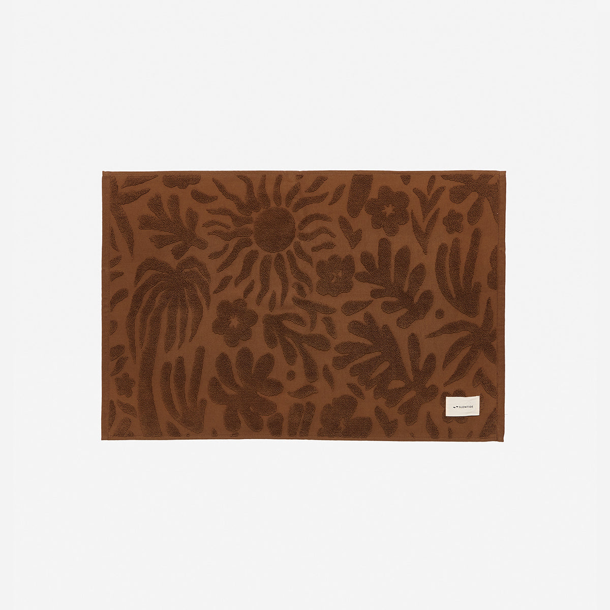 Bath mat, plush rust-colored cotton with floral and sun design, 1000 GSM label in corner.