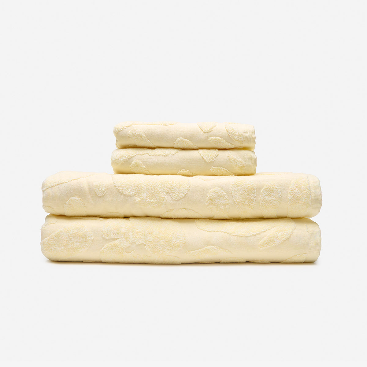 Cream bath towels with subtle textured pattern stacked.