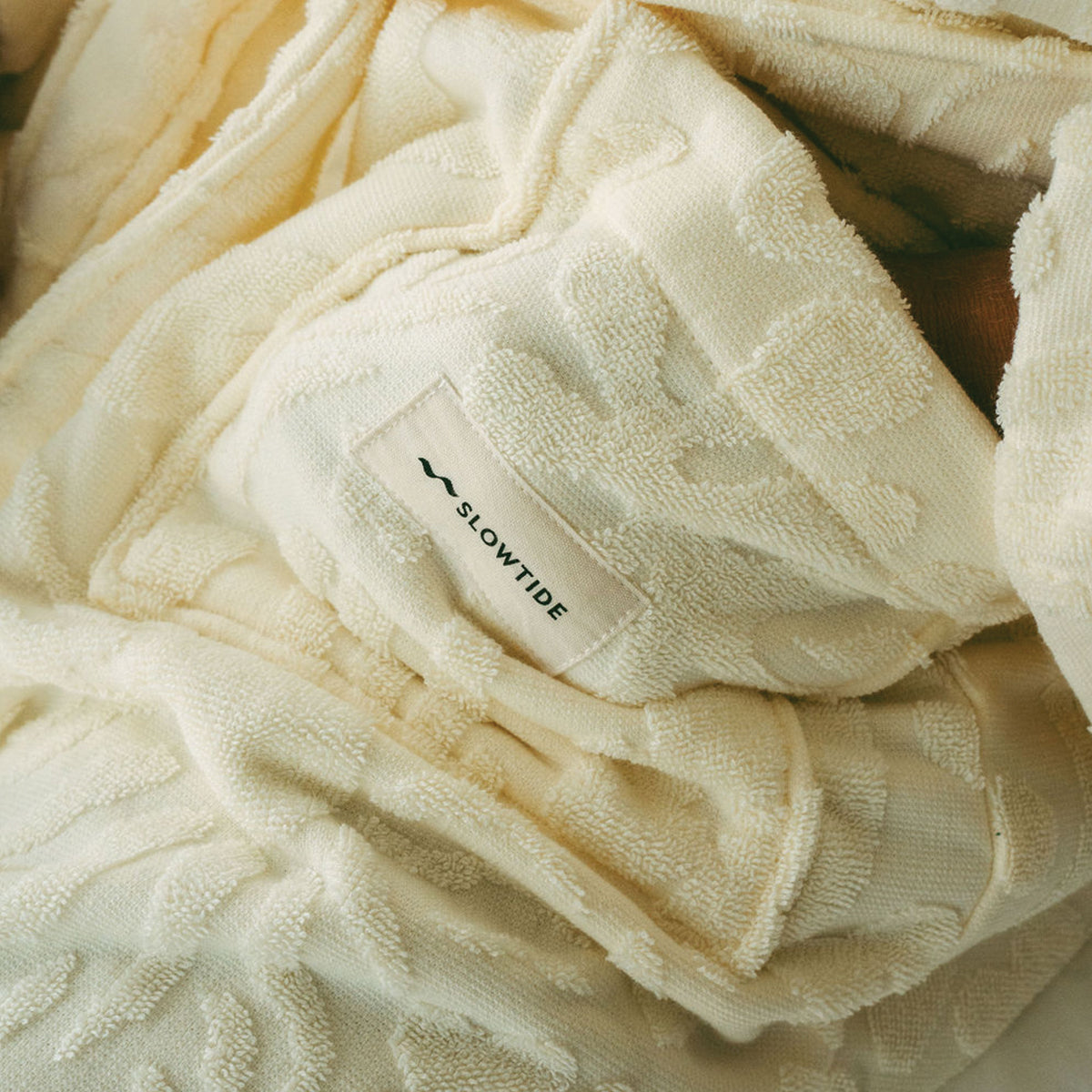Plush bathrobe in cream with a logo patch.