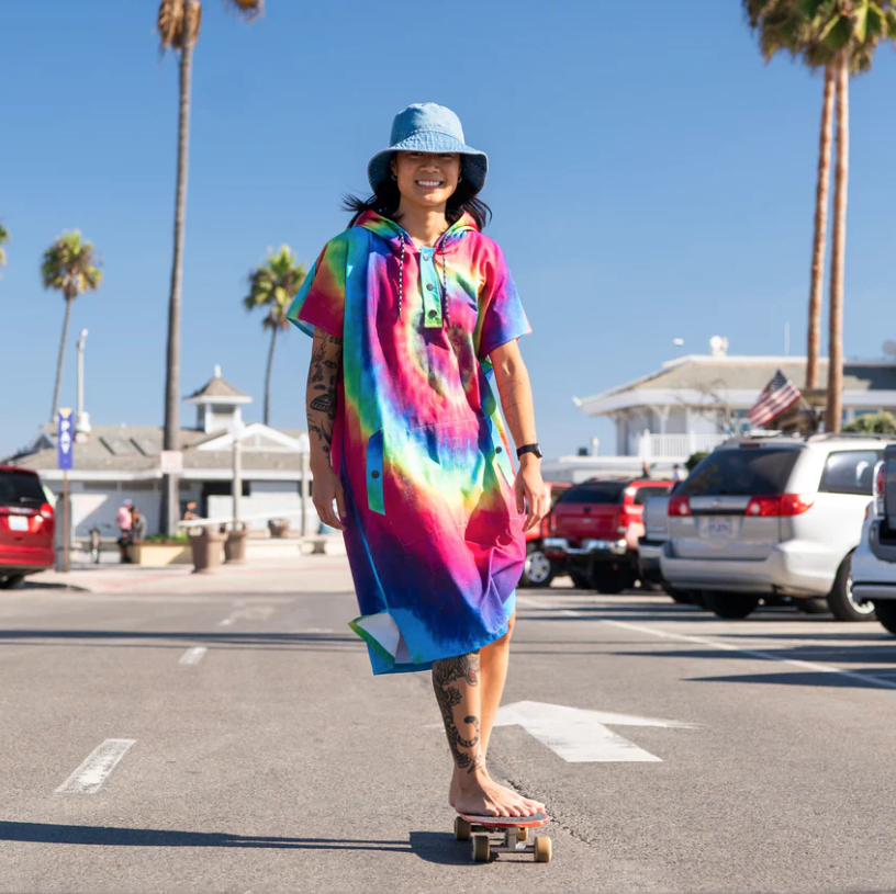 girl wearing tiedye changing poncho on skateboard