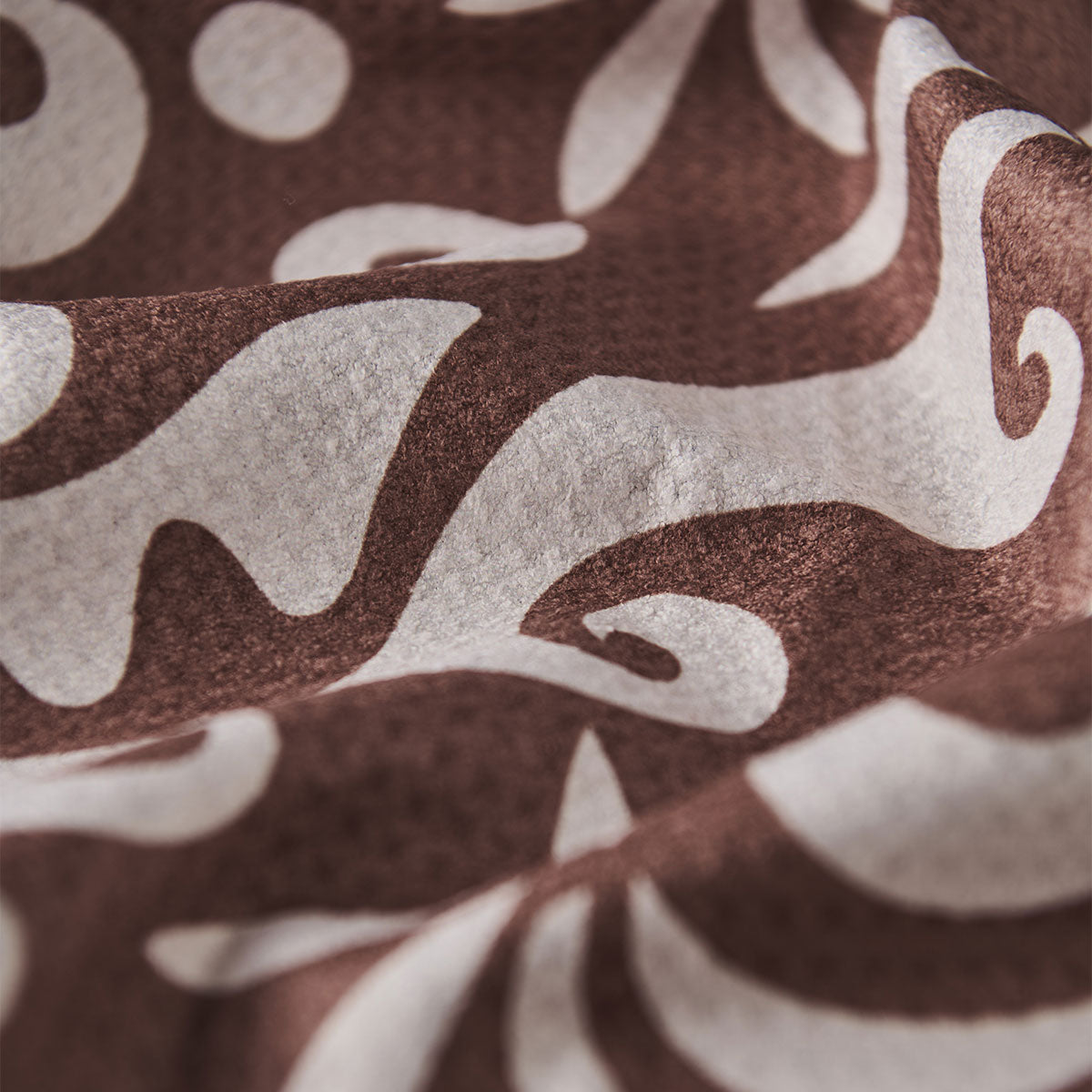 Sand resistant towel with white abstract and floral patterns, close-up of fabric texture.