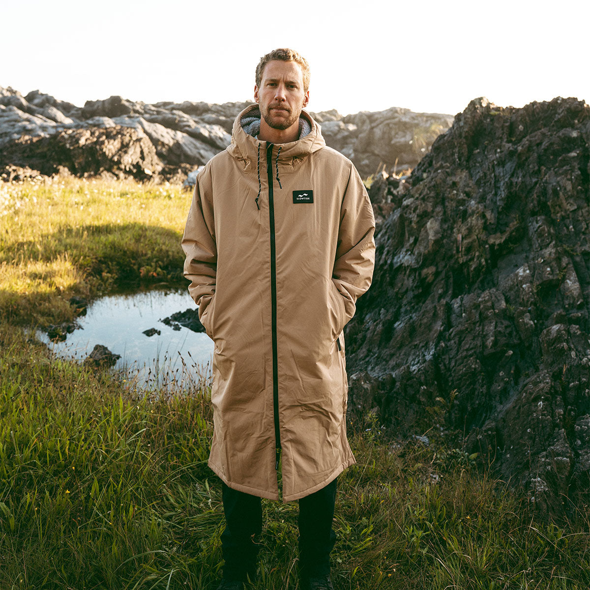 Tan all-weather parka with hood on grass outdoors.