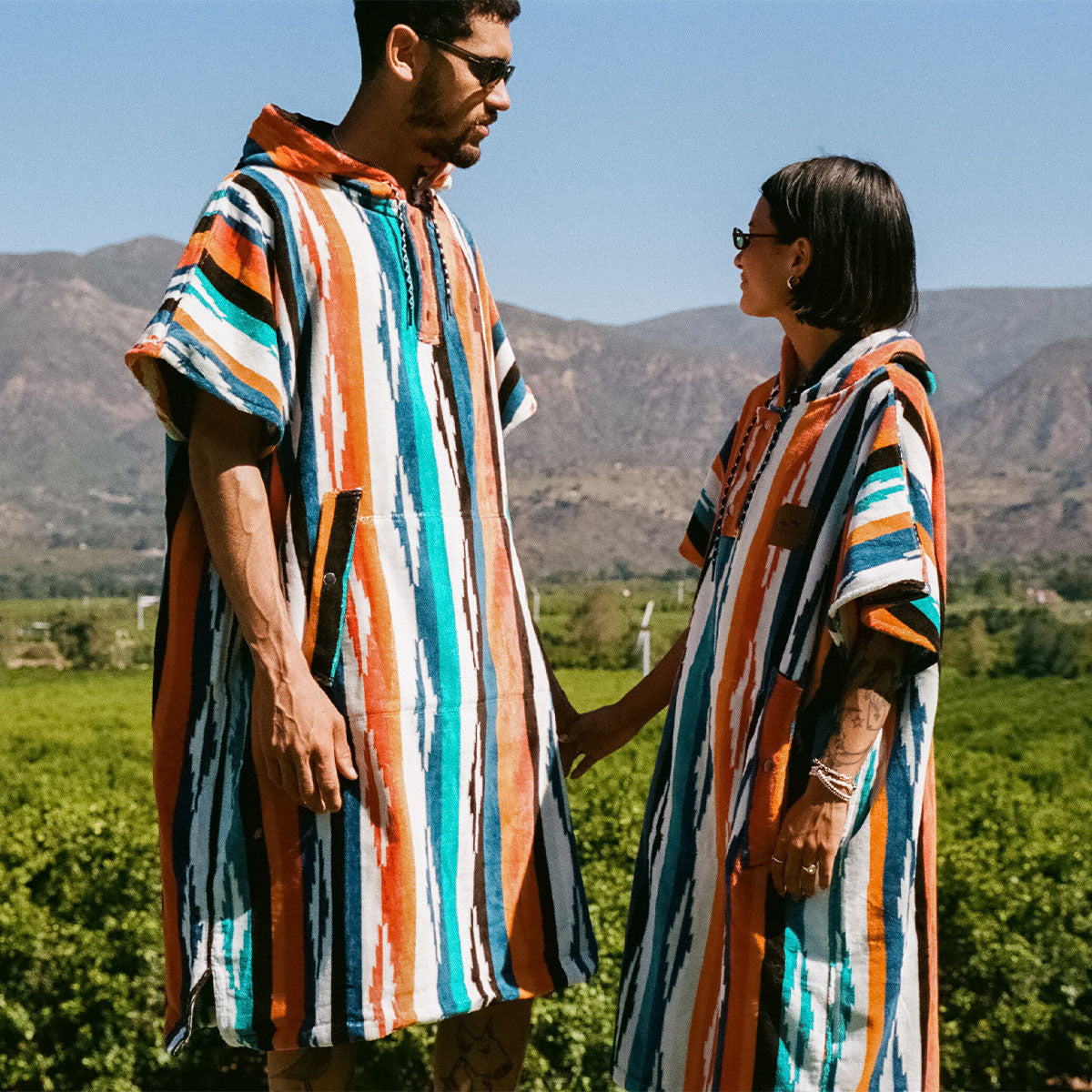 Cotton terry towel ponchos with colorful stripes outdoors.