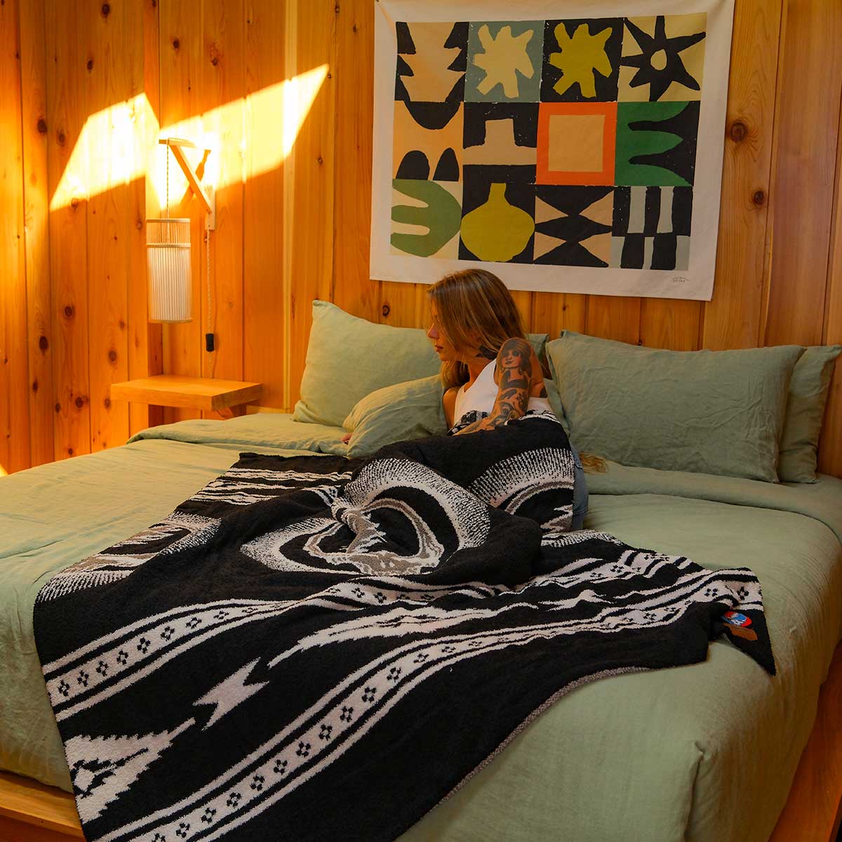 Woven throw blanket featuring Grateful Dead imagery in black and white on a bed.