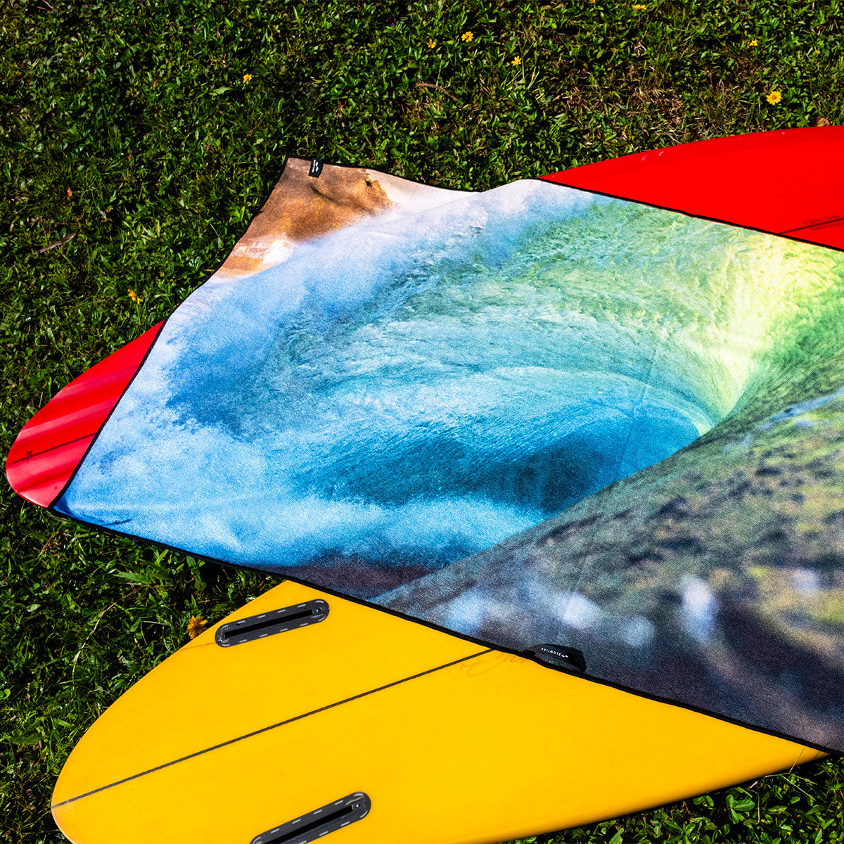 Surf towel with wave print on red and yellow surfboards.