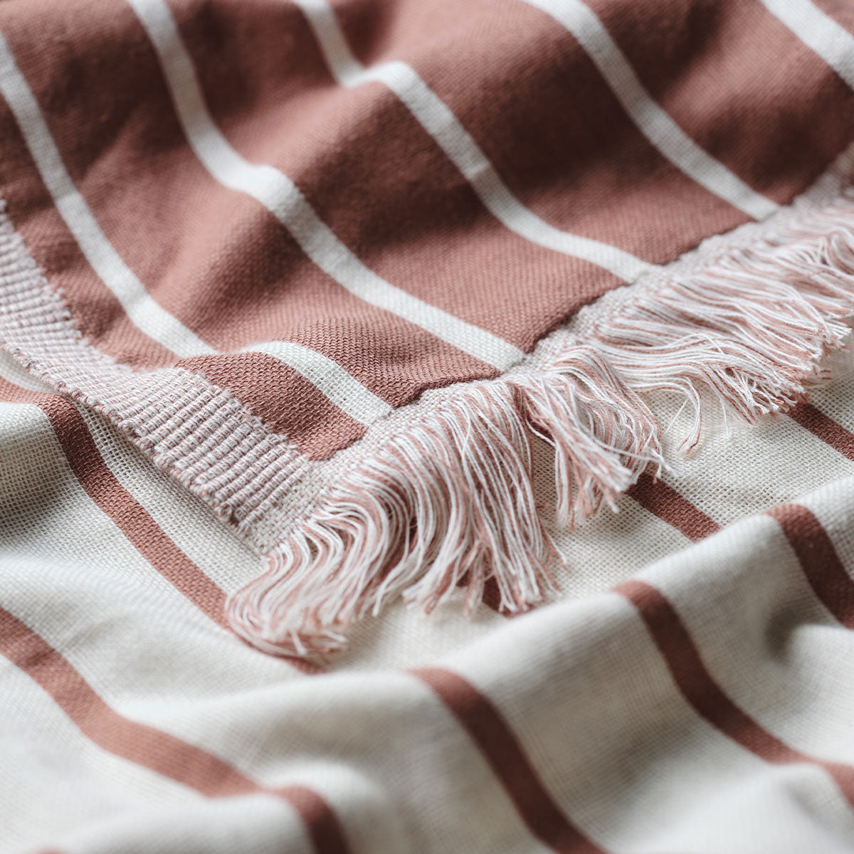 Reversible fabric with earthy tones and terracotta stripes, lightweight texture shown up close.