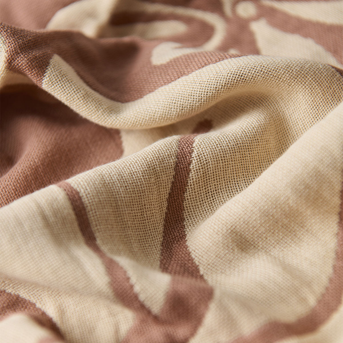 Cotton towel with beige and brown pattern, gauzy texture, and soft visible folds.