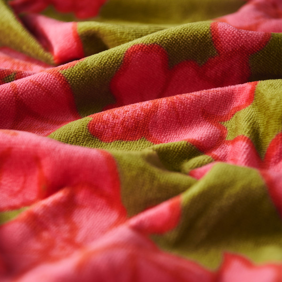 Velour fabric with red floral pattern on green, textured folds visible.