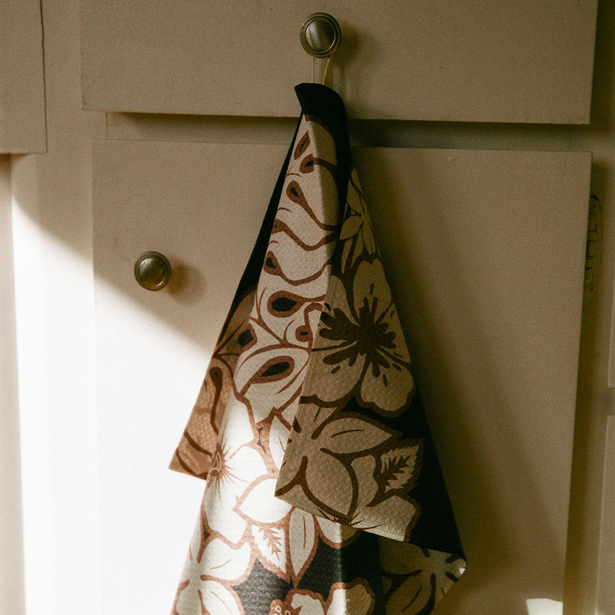 Oversized towel with floral pattern hanging on a hook.