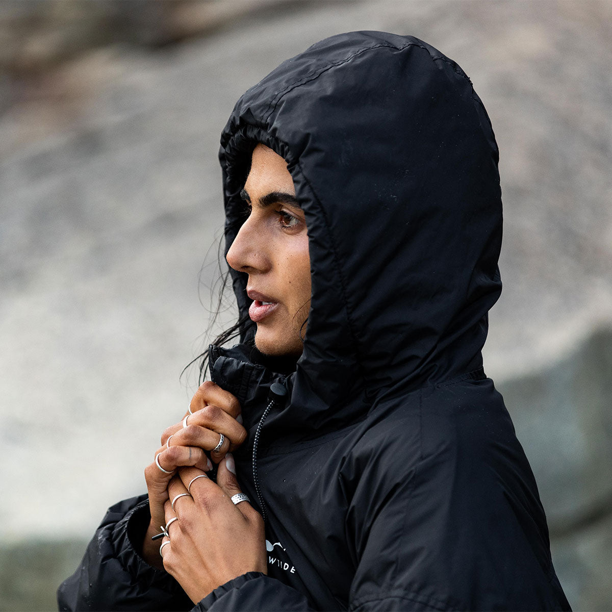 Black hooded all-weather parka with adjustable collar, outdoor setting.