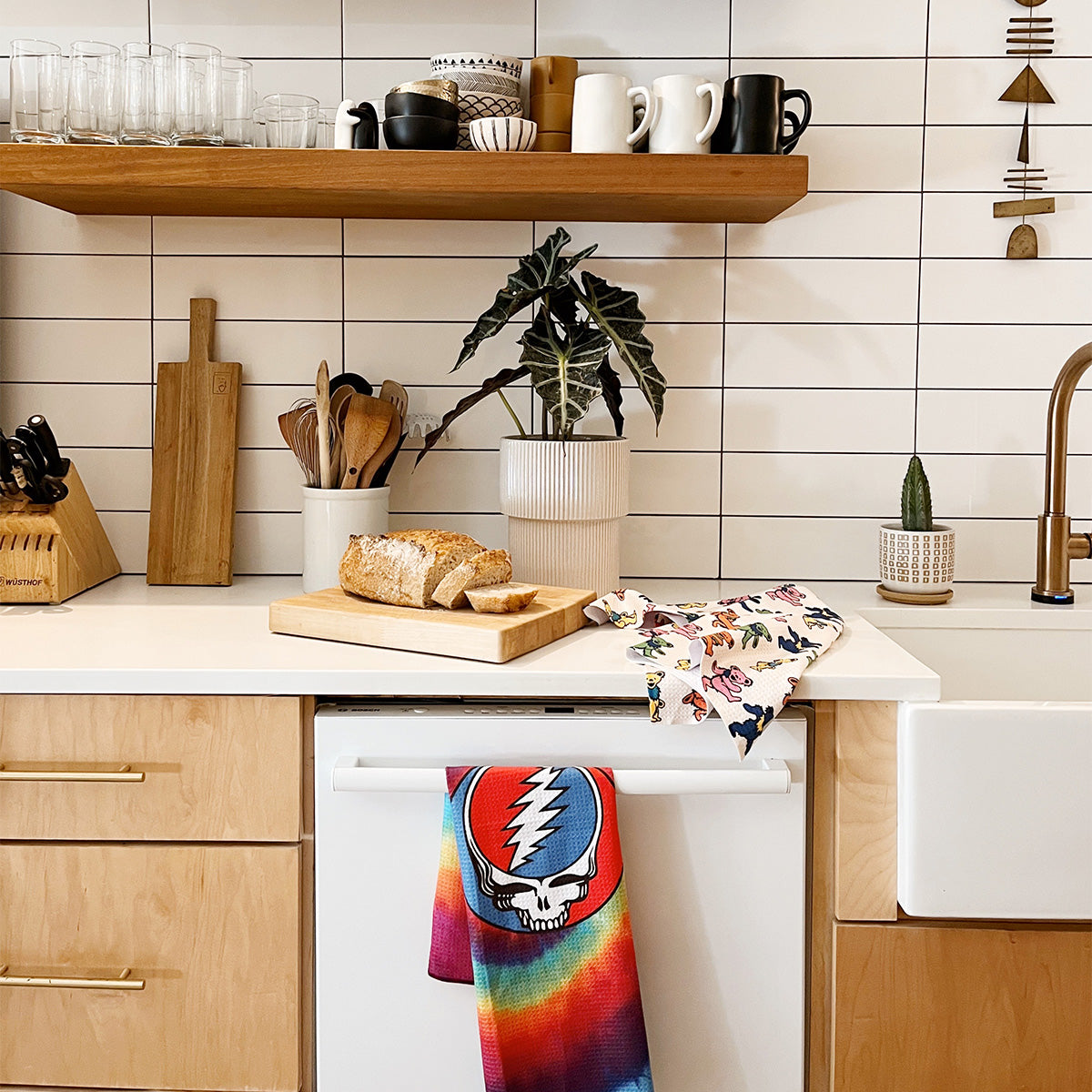 Kitchen towel with tie-dye lightning bolt skull design hanging on a dishwasher handle.