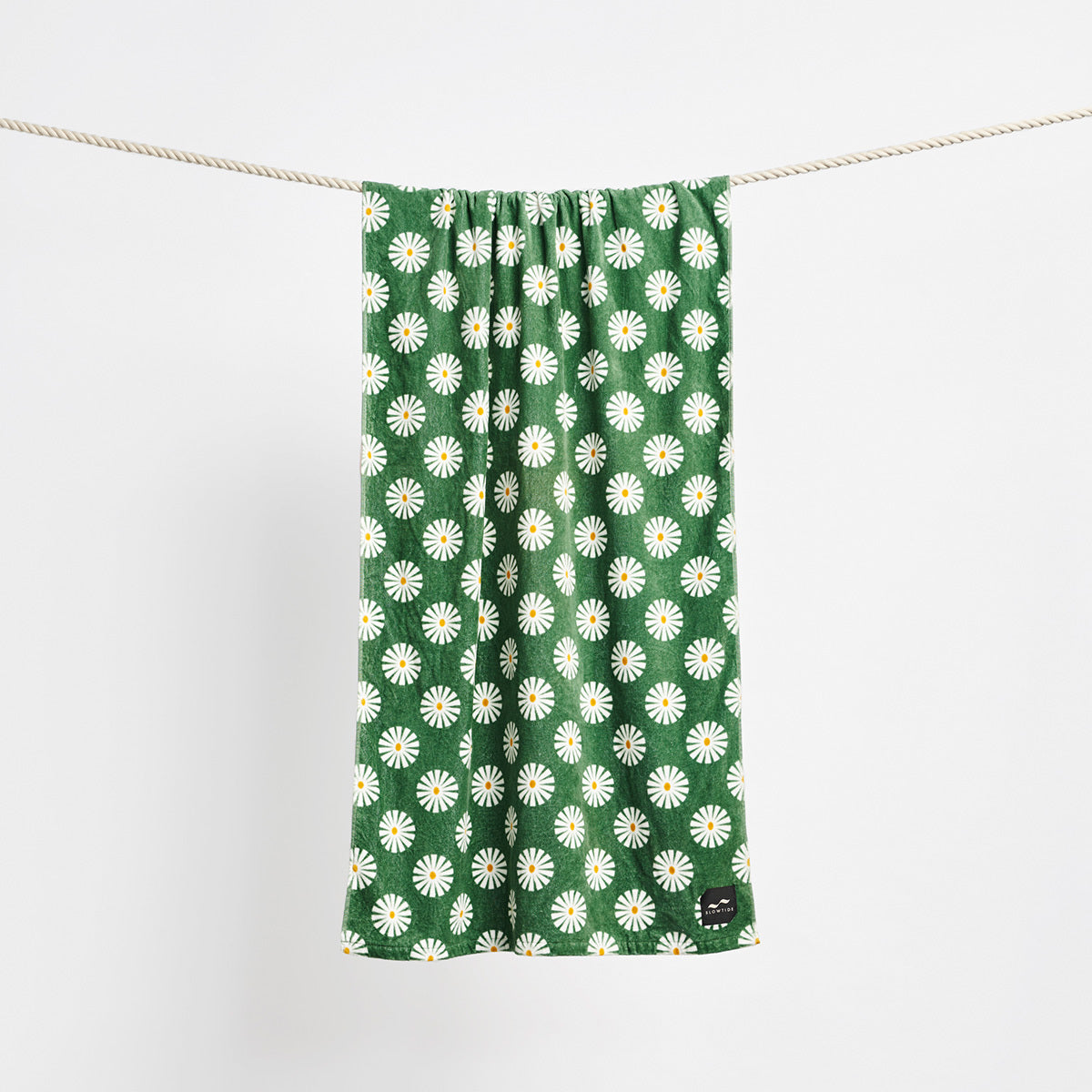 Cotton towel with white and yellow daisy pattern hanging on a rope.