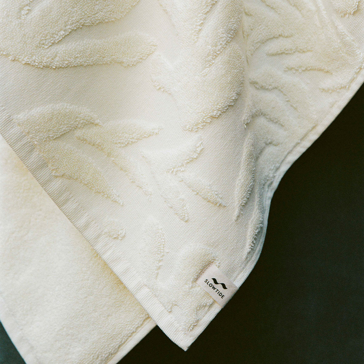 Cotton towel with sculpted floral pattern and small label on the edge.