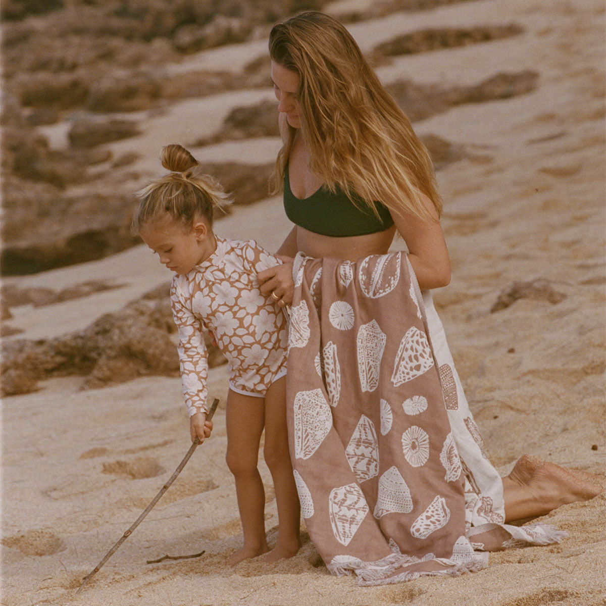 Sand-resistant towel with child-safe surface, shown in use on the beach.