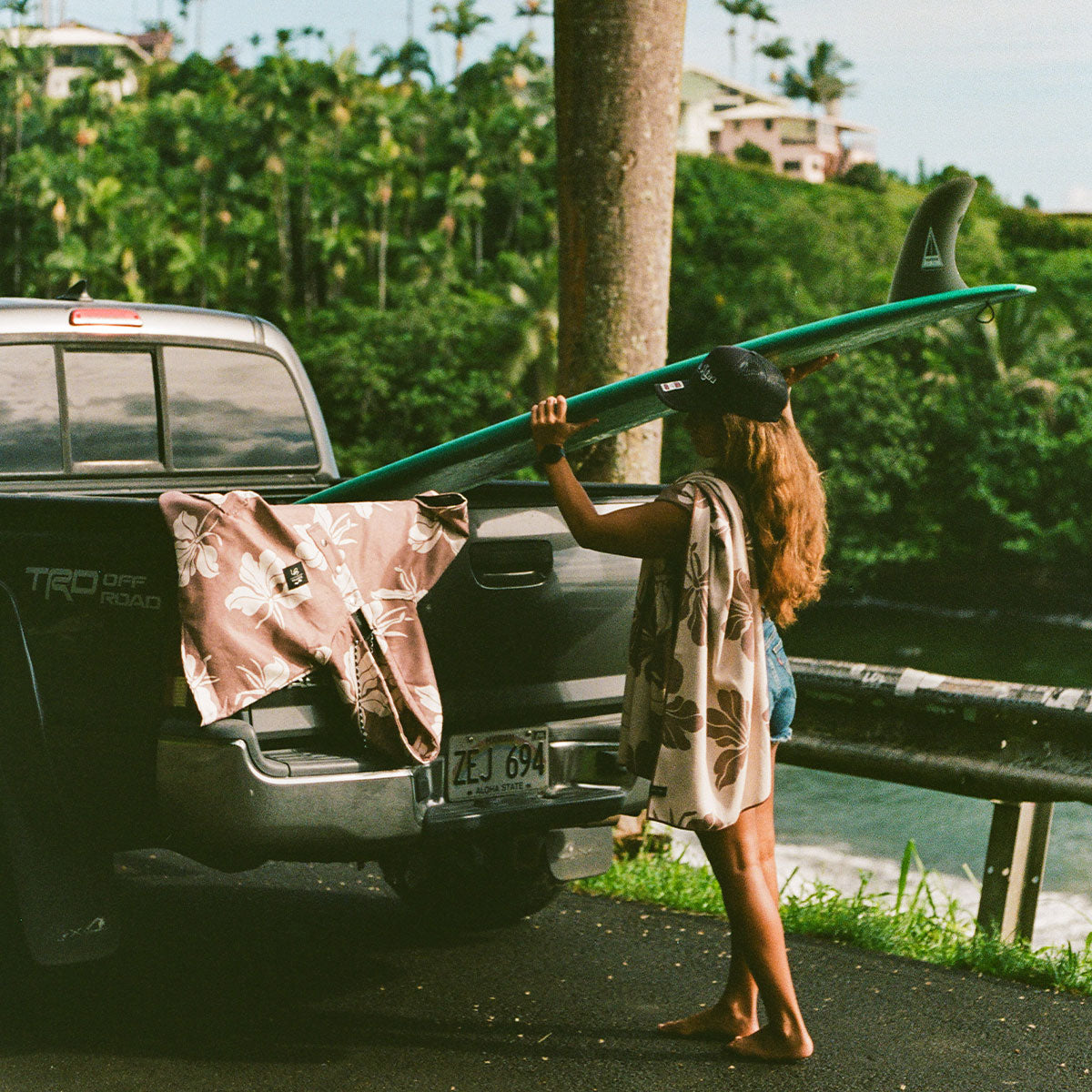 Recycled material quick-dry poncho in brown floral print on a truck tailgate with a surfboard.