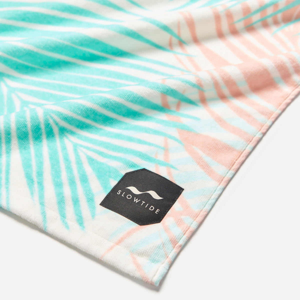 Cotton towel with pastel palm leaf pattern, absorbent, suitable for bath or beach use.