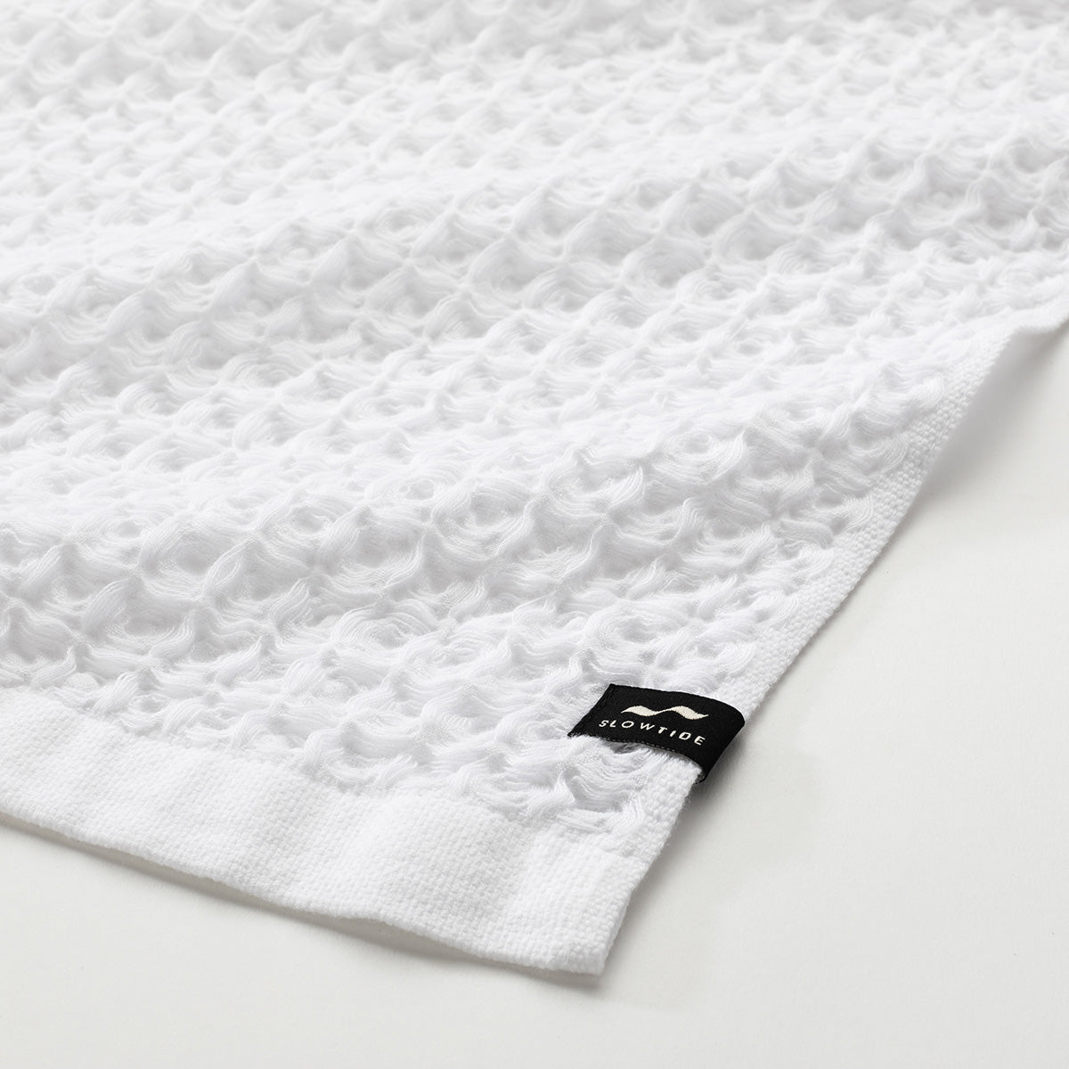 White waffle bath towel with small black tag in the corner.