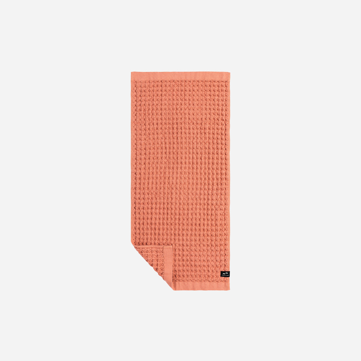 Quick dry coral towel with waffle texture, folded neatly.